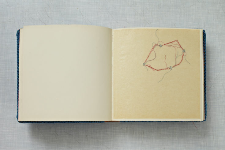 „Familienalbum“, 2011, Fotoalbum mit blauem Garn umhäkelt, mit 38 Nadelstickereien in Pergamentpapier, Buch: 26 x 27 x 4 cm, Tisch: 74 x 90 x 60 cm, © Sylvie Hauptvogel, Foto: Sigurd Steinprinz