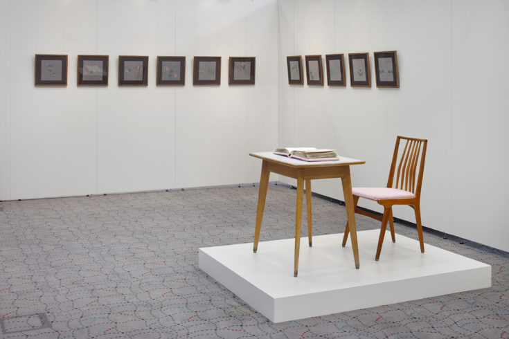 Im Vordergrund „zartes Rosa“ und im Hintergrund „Nadelarbeiten 1–11“, „zartes Rosa“, Tisch, Fotoalbum und Stuhl, Buch und Sitzfläche mit rosa Garn umhäkelt, Tisch:71 x 77 x 55 cm, Stuhl: 83 x 45,5 x 43 cm, Buch: 26 x 27 x 7 cm. „Nadelarbeiten 1–11“, 2014/2015, Pergamentpapiere aus dem Fotoalbum, Nähgarn, Maße mit Rahmen: 37,3 x 37,3 cm, Raumansicht Sparkasse Wuppertal 2015, © Sylvie Hauptvogel, Foto: Sigurd Steinprinz