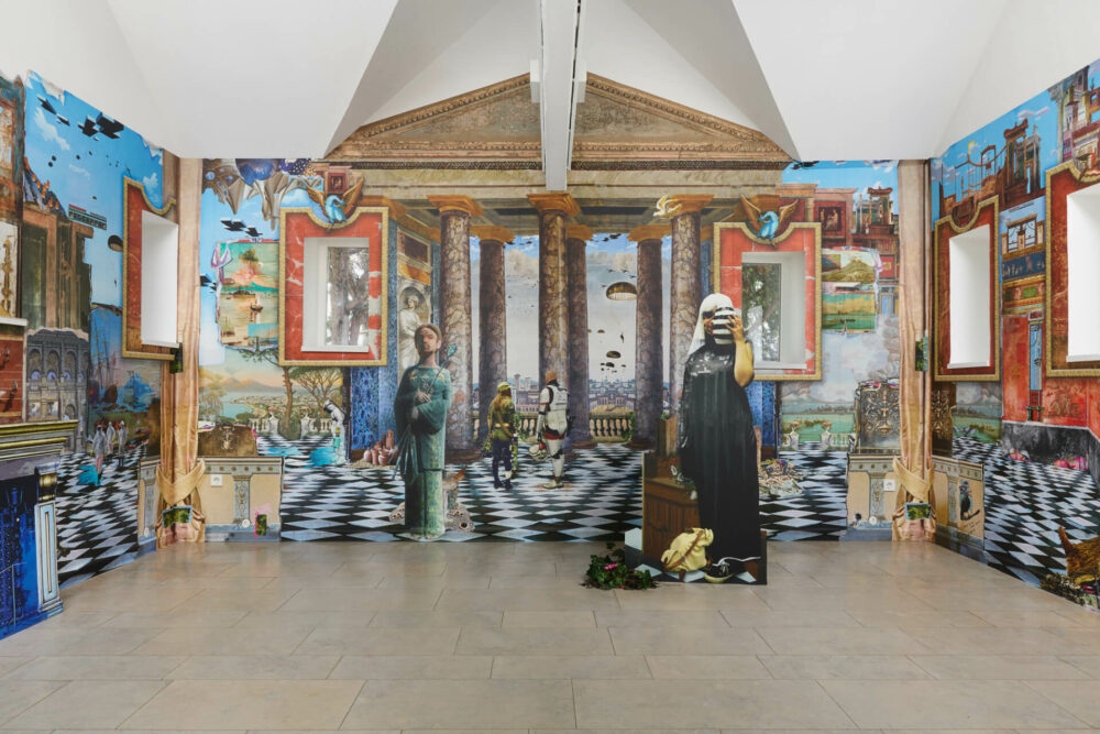 Installation „zweijahrtausendfern“, Gerhard Marcks Haus Bremen, 2022, Raumansicht frontal, im Digitaldruckverfahren hergestellte Tapete, Konturfiguren, Holzkonstruktion, Camouflage-Netz, Kontursäulen-Fototapete, Camouflage-Klebeband, künstliches Efeu, künstliche Pflanzen, Postkarten, Postkartenstände, Wandkonsole, Putte antik, Kerze, goldfarbenes Tondo, Stuckgipssäulen, Sandsäcke, 320 x 525 x 460 cm © VG Bild-Kunst, Bonn 2025 / Patricia Lambertus, Foto: Tobias Hübel