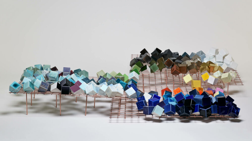 La Bibliothèque est en feu, 2018, Sèvres Porzellan und Glasuren, Metallgitter aus Stahl mit Kupferschicht, Künstlerbuch der Rezepte, Cubes jeweils 6 x 6 x 6 cm, Metallsockel jeweils 92 x 92 x 20 cm, Foto: Gérard Jonca, Courtesy of Sèvres/Cité de la céramique